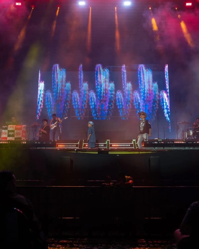 El escenario del Foro Principal con luces rojas y doradas, la pantalla de colores y la banda en vivo