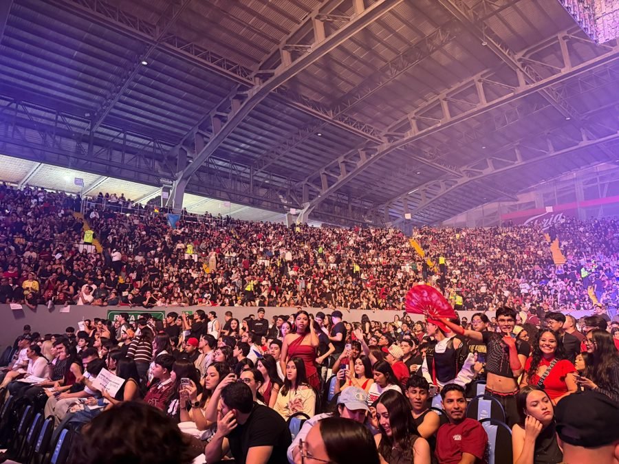 Gradas llenas del Auditorio Jalisco; en primer plano fans con abanicos rojos, playeras de la gira y cartulinas