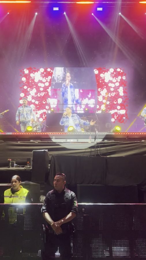 El escenario del Foro Principal con flores en la pantalla y el público de pie