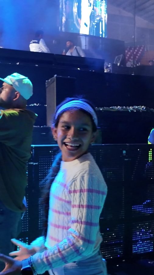 Una pareja baila abrazada en la pista del Foro, con luz morada y el escenario al fondo