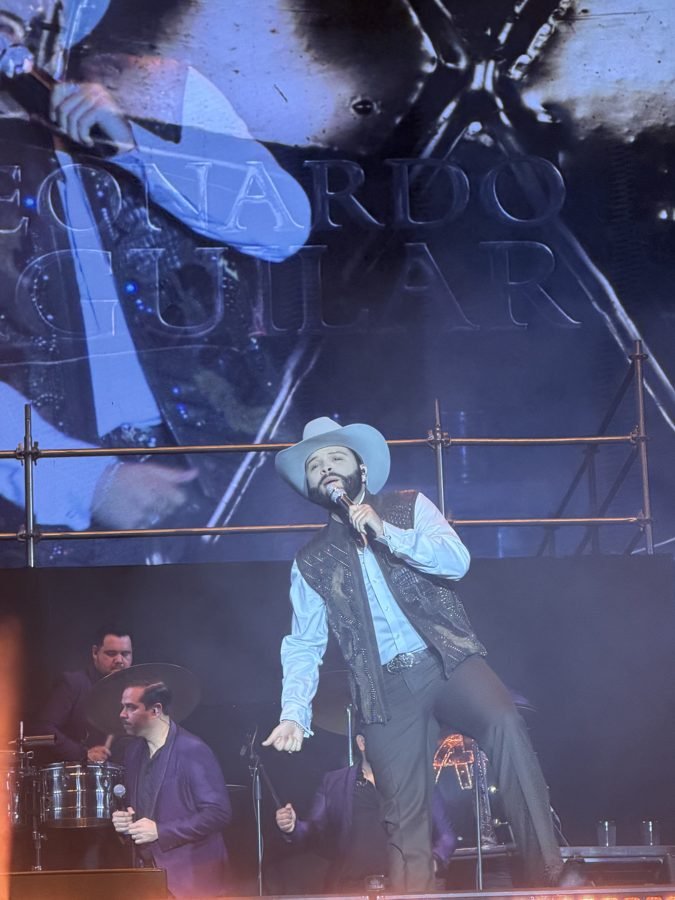 Leonardo Aguilar canta con chaleco bordado y sombrero frente a la pantalla con su nombre