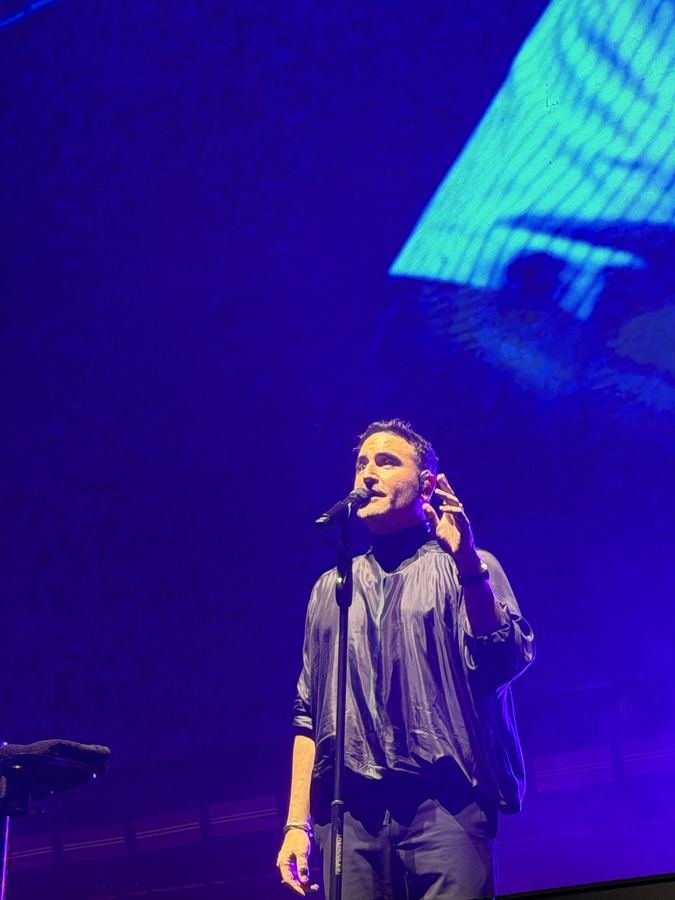 Jesús Navarro canta con la mano en el pecho frente a una pantalla azul