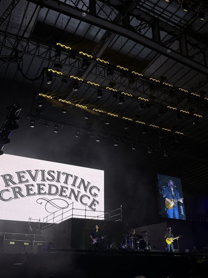 El escenario con la pantalla del logo y una pantalla lateral con el guitarrista en primer plano