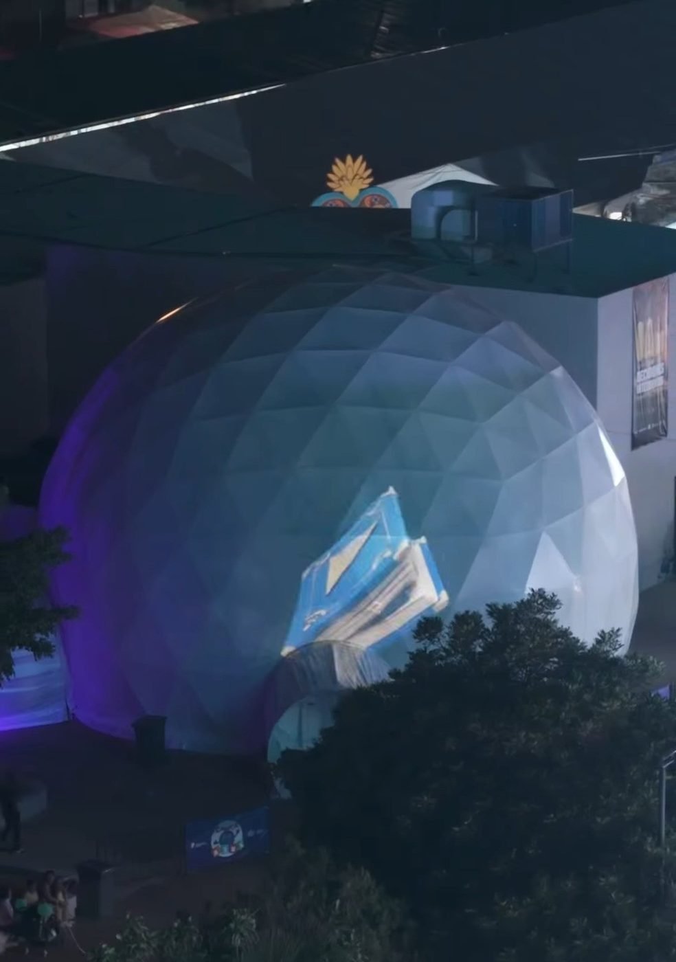 La Domósfera grande de noche con una ballena y un globo aerostático proyectados en su cúpula
