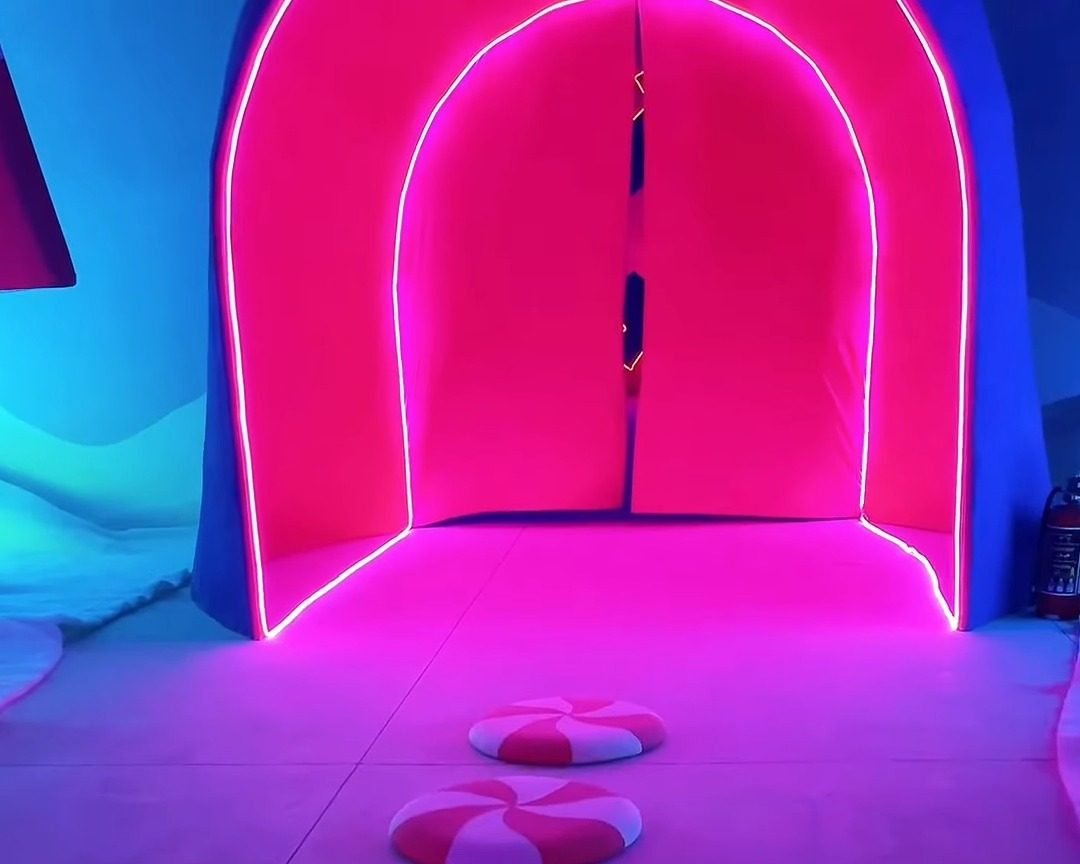 Pasillo rosa con un arco de neón y caramelos de menta en el piso